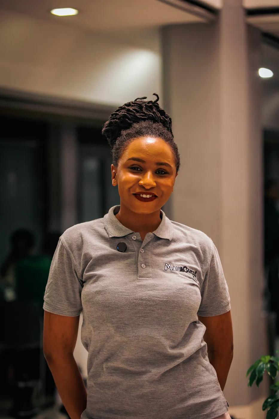 A smiling woman in a grey Chess254 club polo at the clubhouse