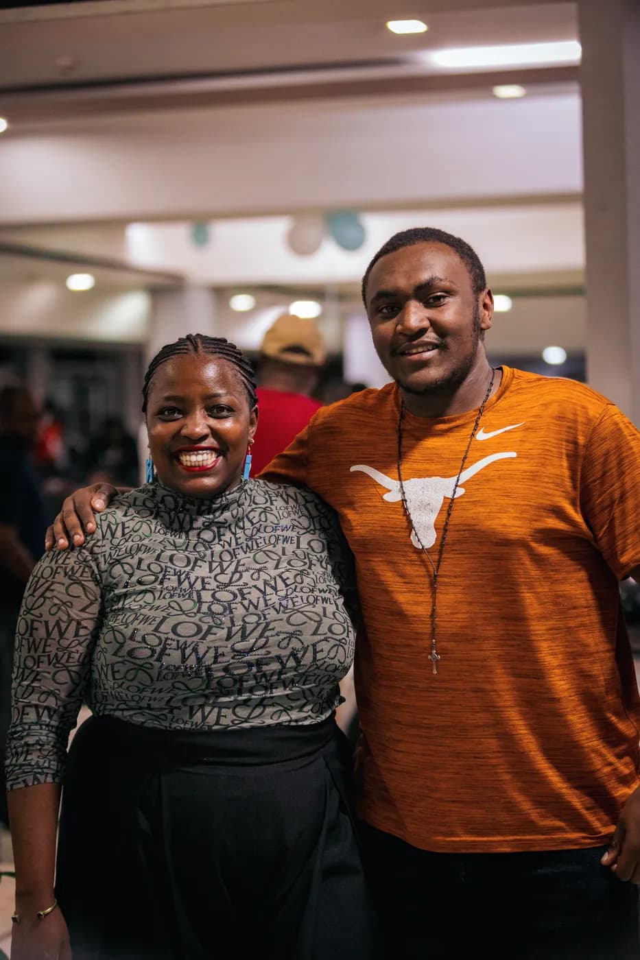 A man in an orange Longhorns top and a woman in a grey patterned top smile together at the clubhouse