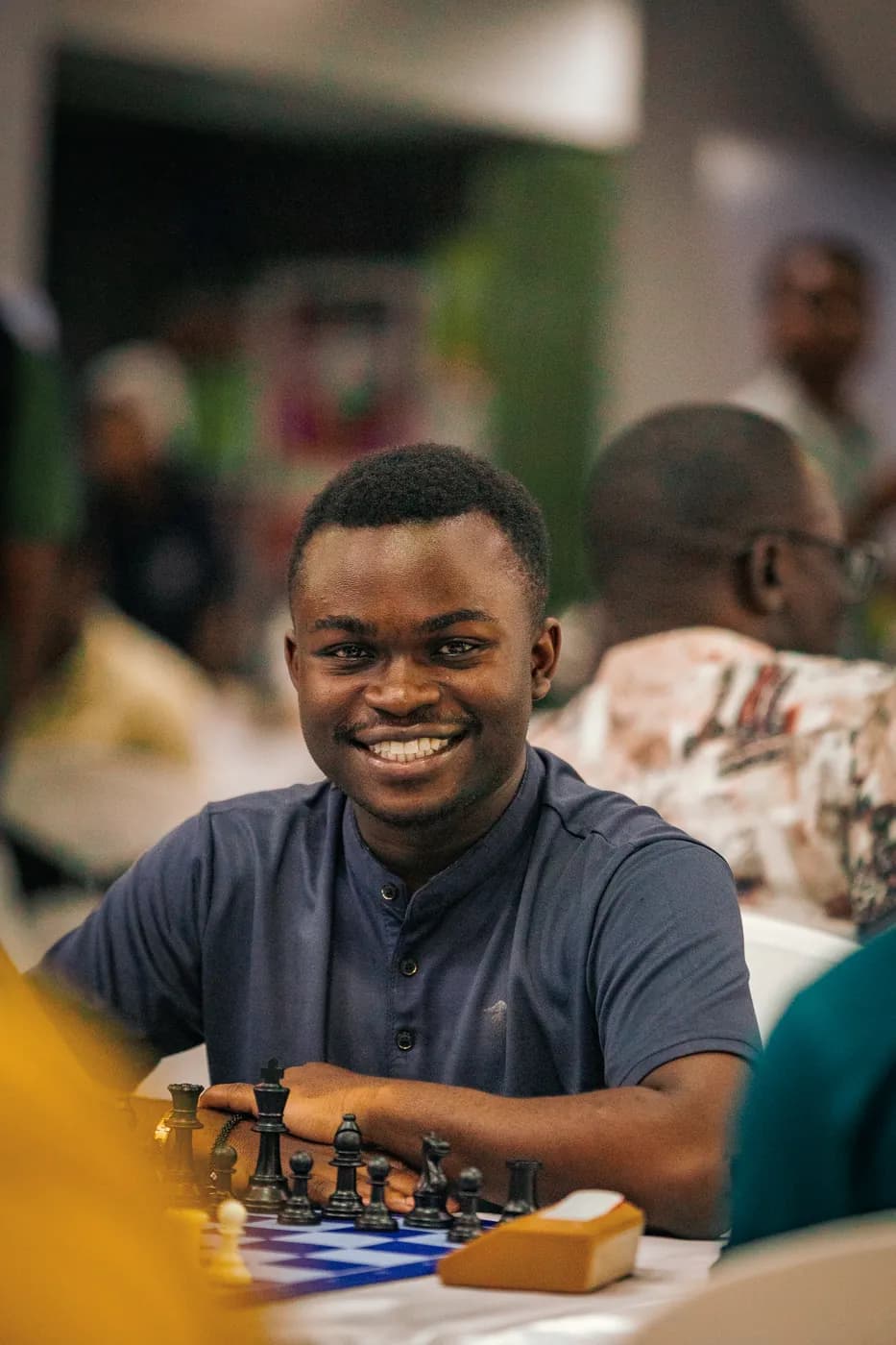 A young man in a navy shirt smiles across a blue board